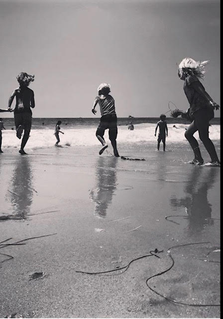 Children playing joyfully on the beach, running and jumping with their reflections in the wet sand